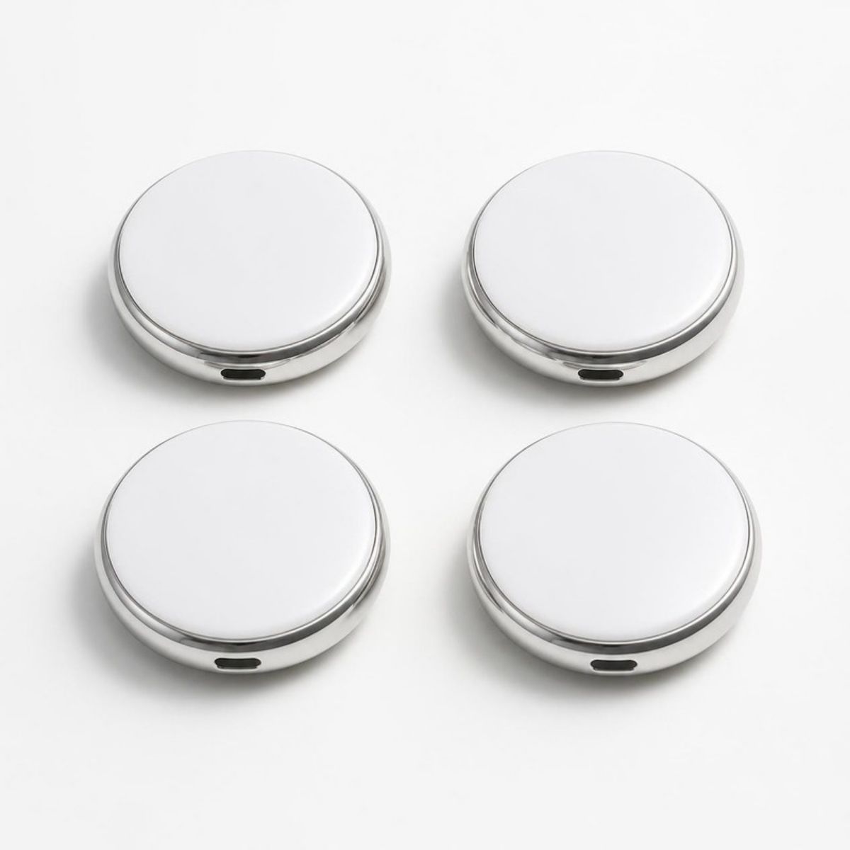Four round white and silver tracker tags