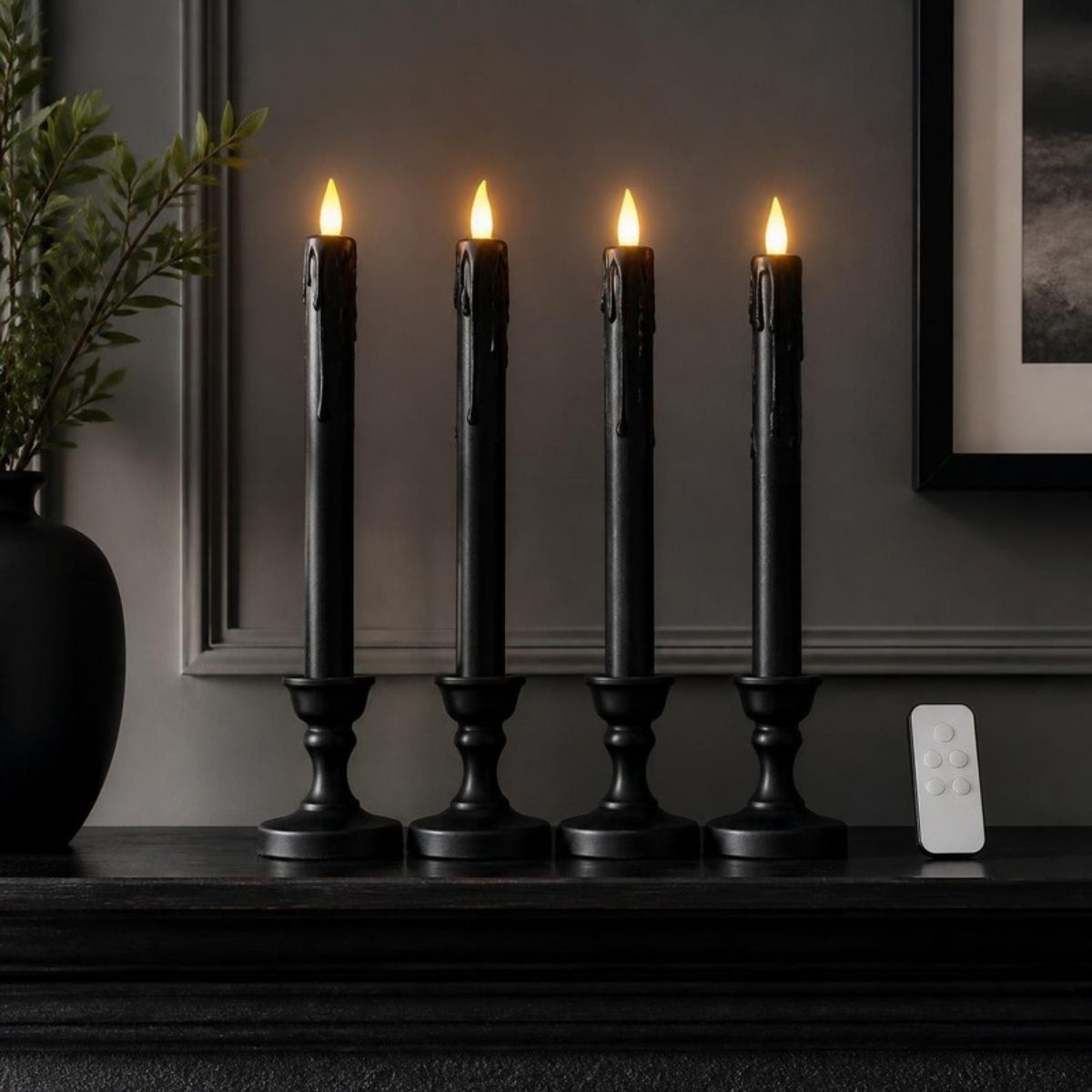Four black drip taper flameless candles in holders with a remote