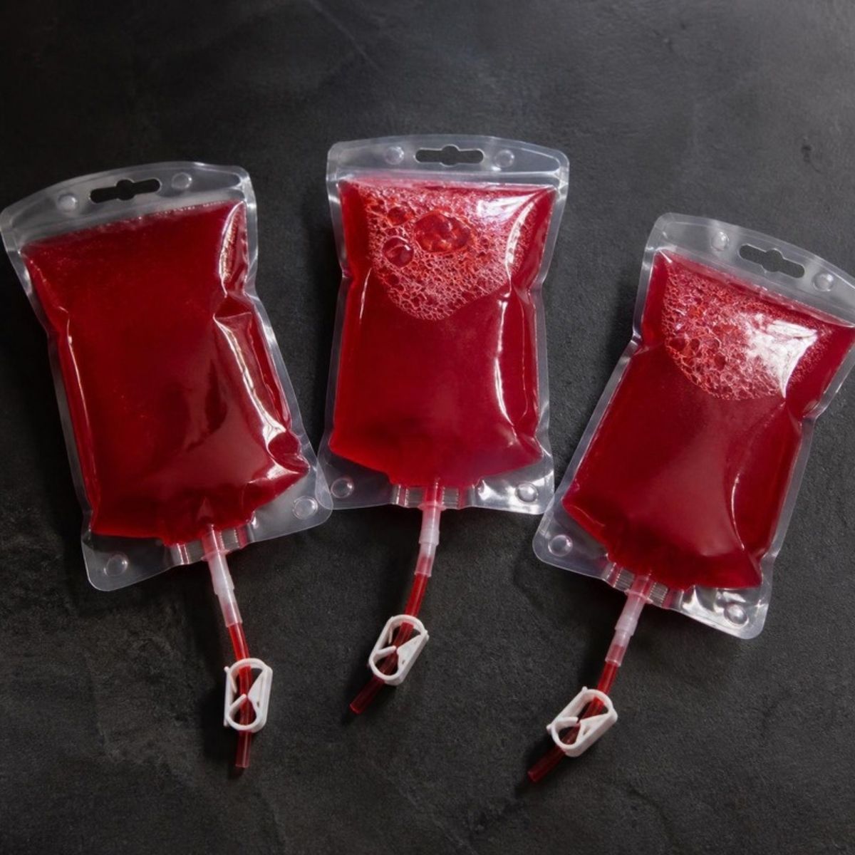 Three blood bag style drink pouches filled with red juice
