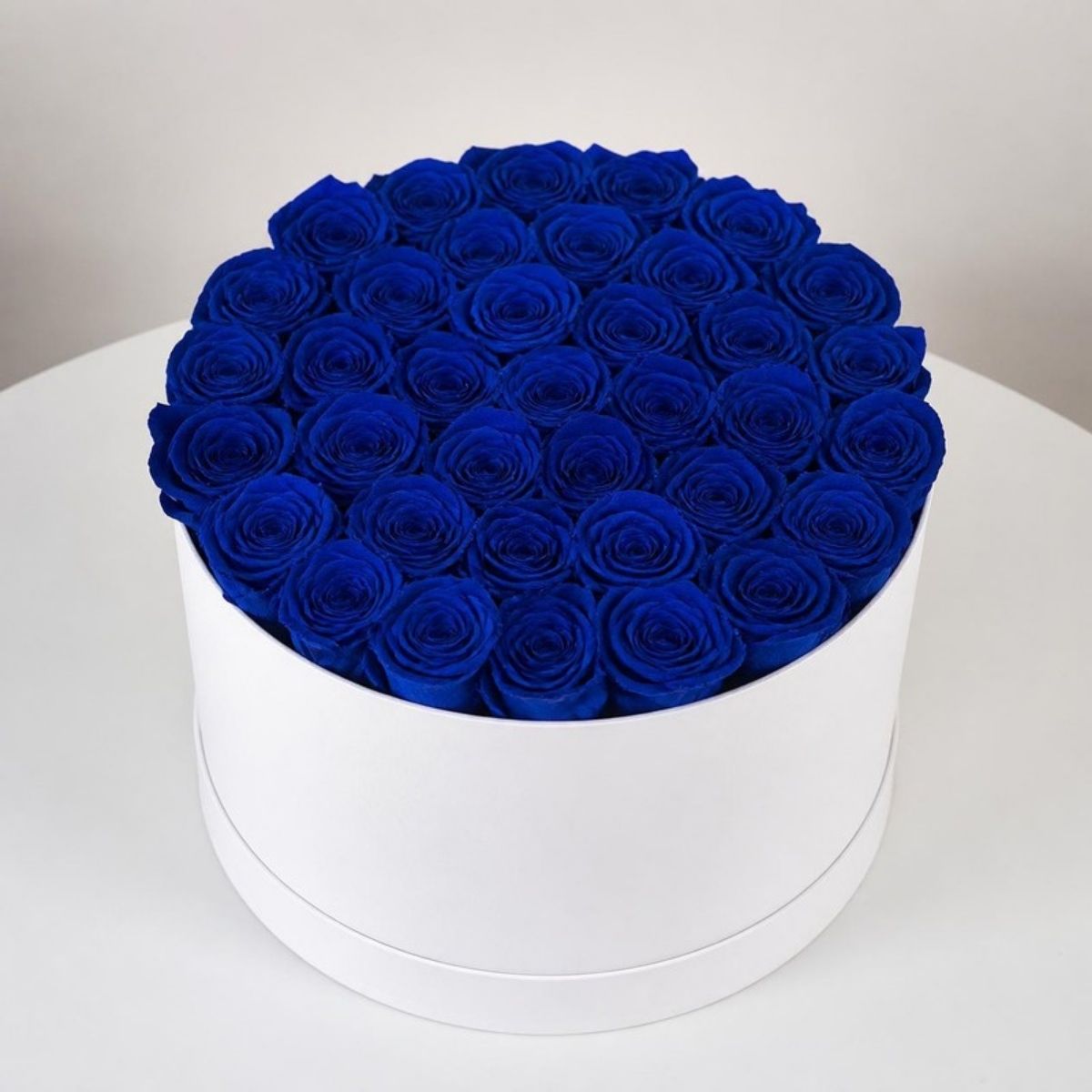 Round white box filled with deep blue roses