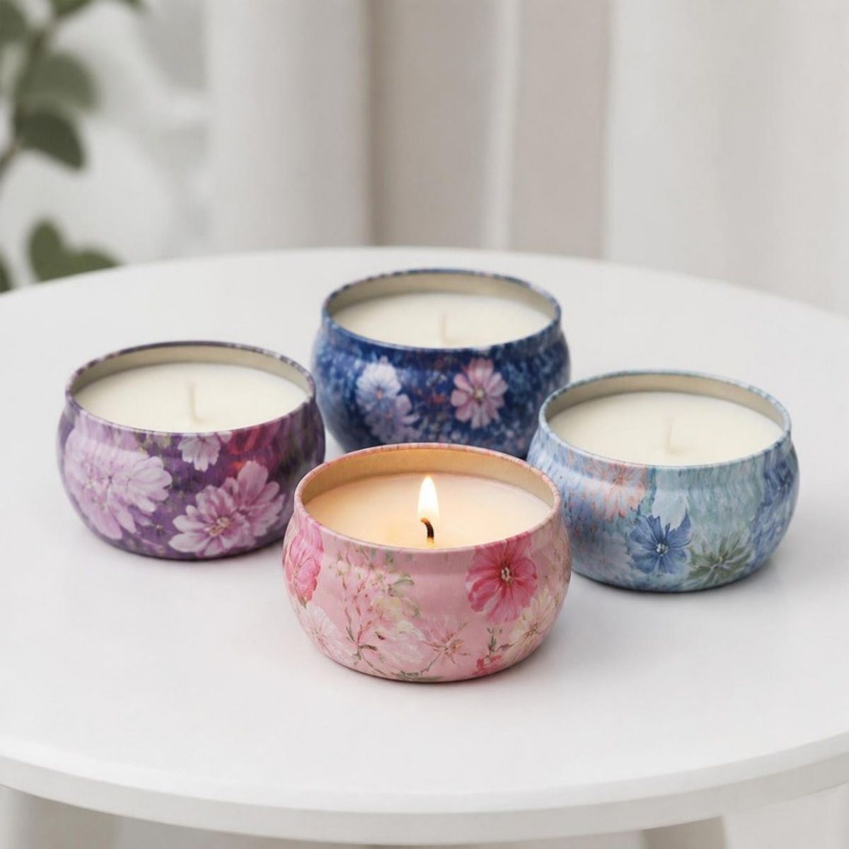 Four patterned candle tins in purple, blue and pink, one lit