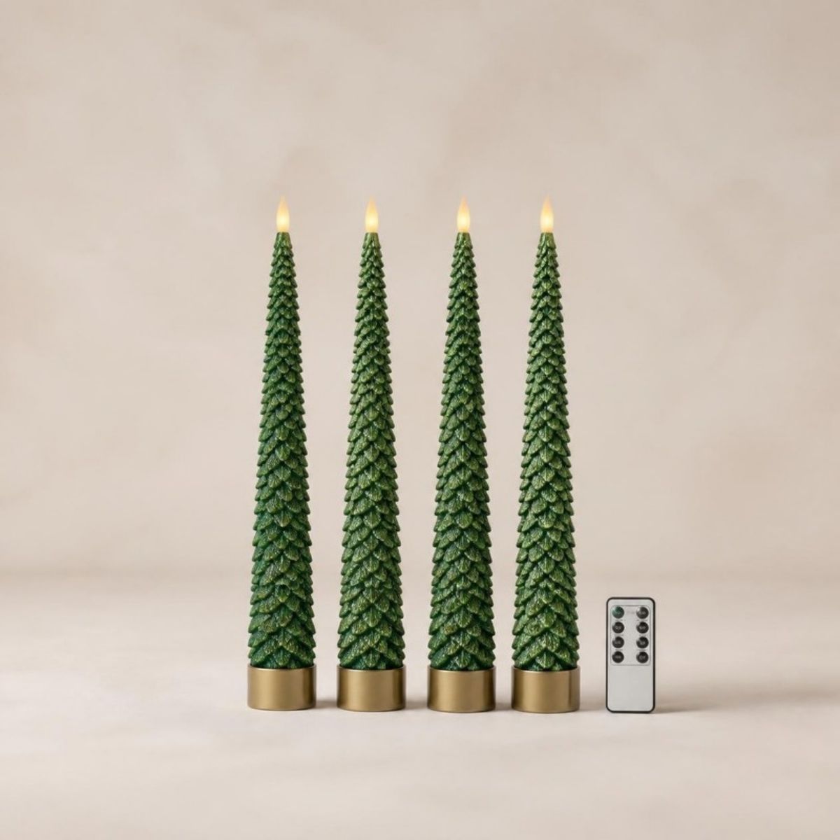 Four green Christmas tree taper candles with flickering flames, gold bases and a remote