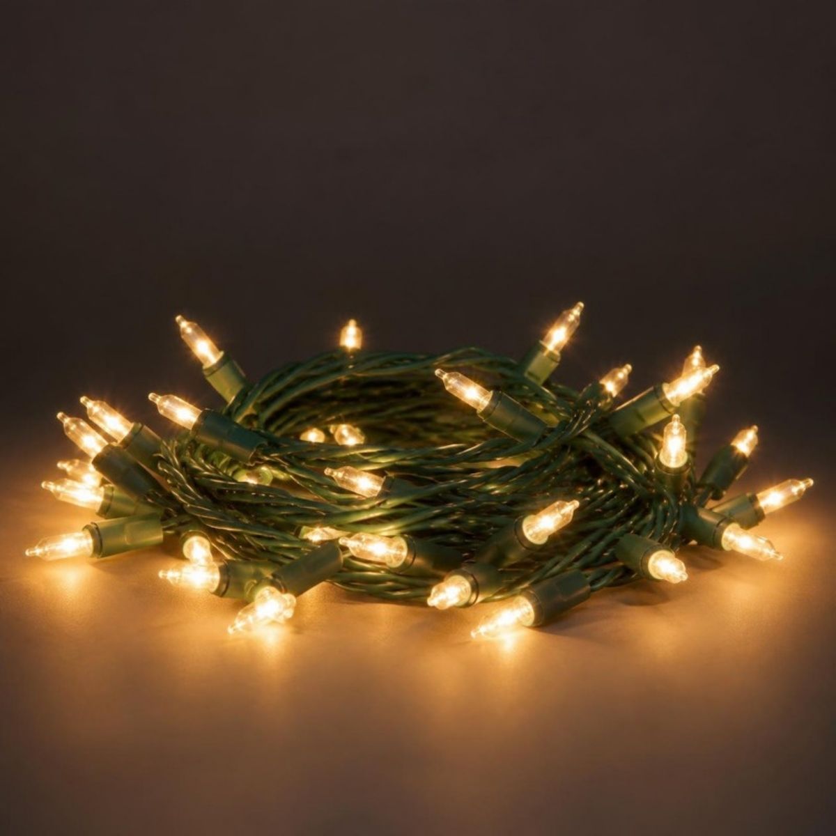 Coil of glowing clear mini Christmas lights on green wire