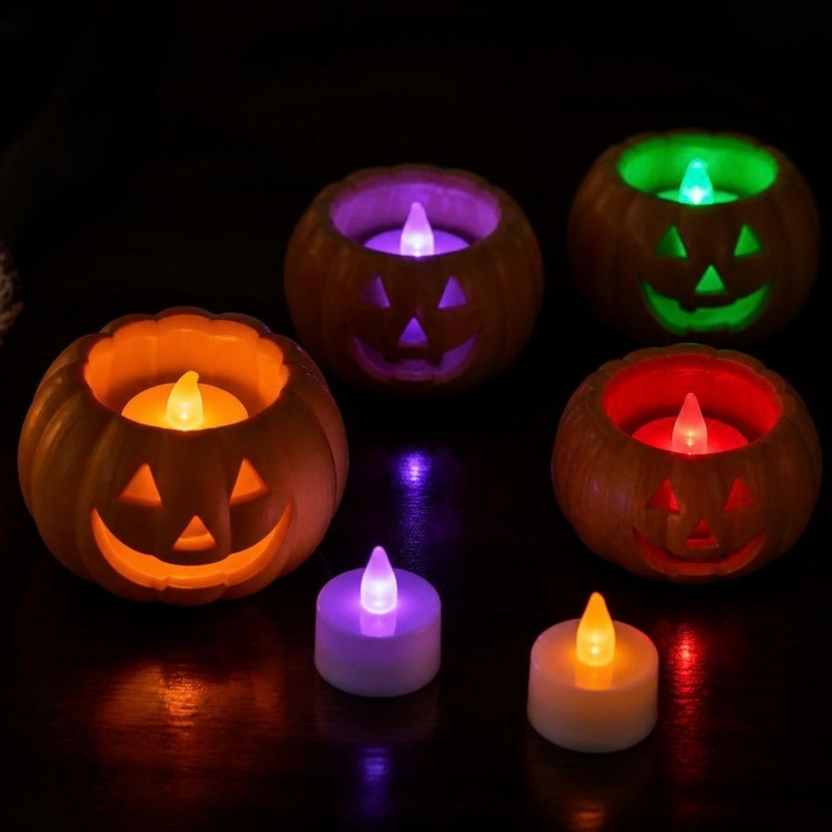 LED tea lights glowing orange, purple, green and red inside small jack o' lanterns