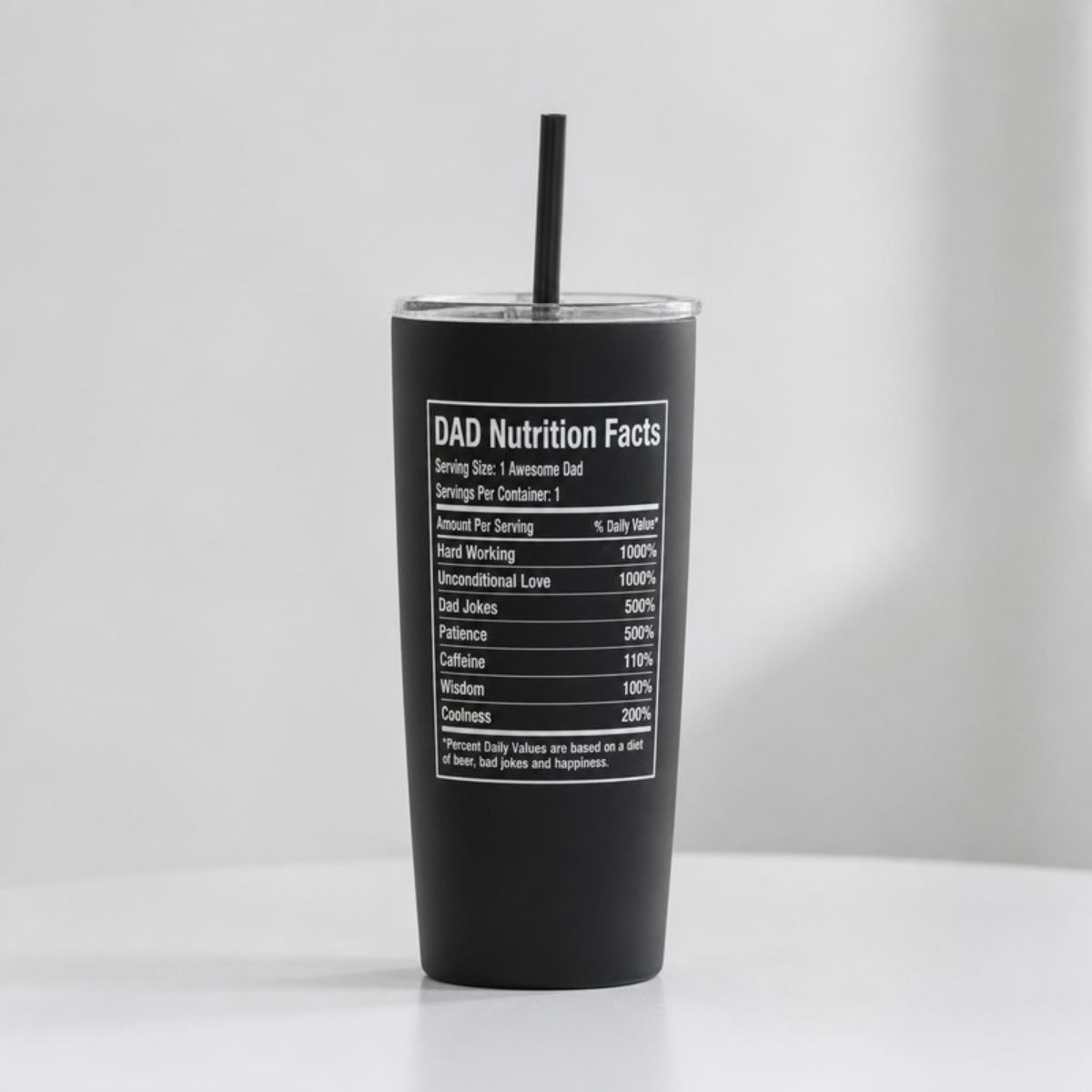 Black tumbler with a straw, printed with a white "DAD Nutrition Facts" label