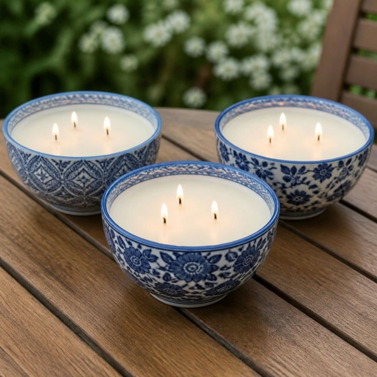 Three blue and white patterned candle bowls, each with three lit wicks