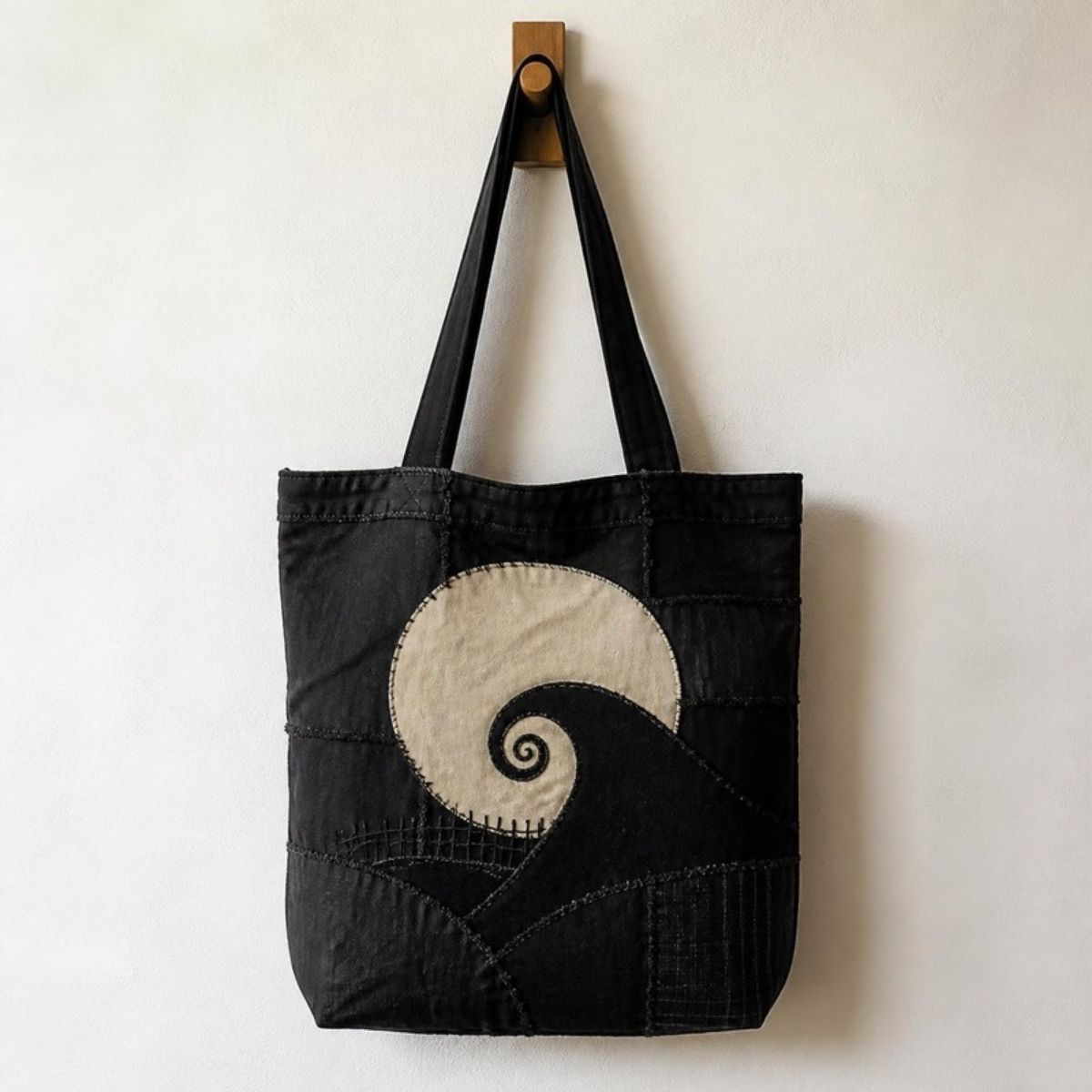 Black patchwork tote bag with a spiral hill and moon design