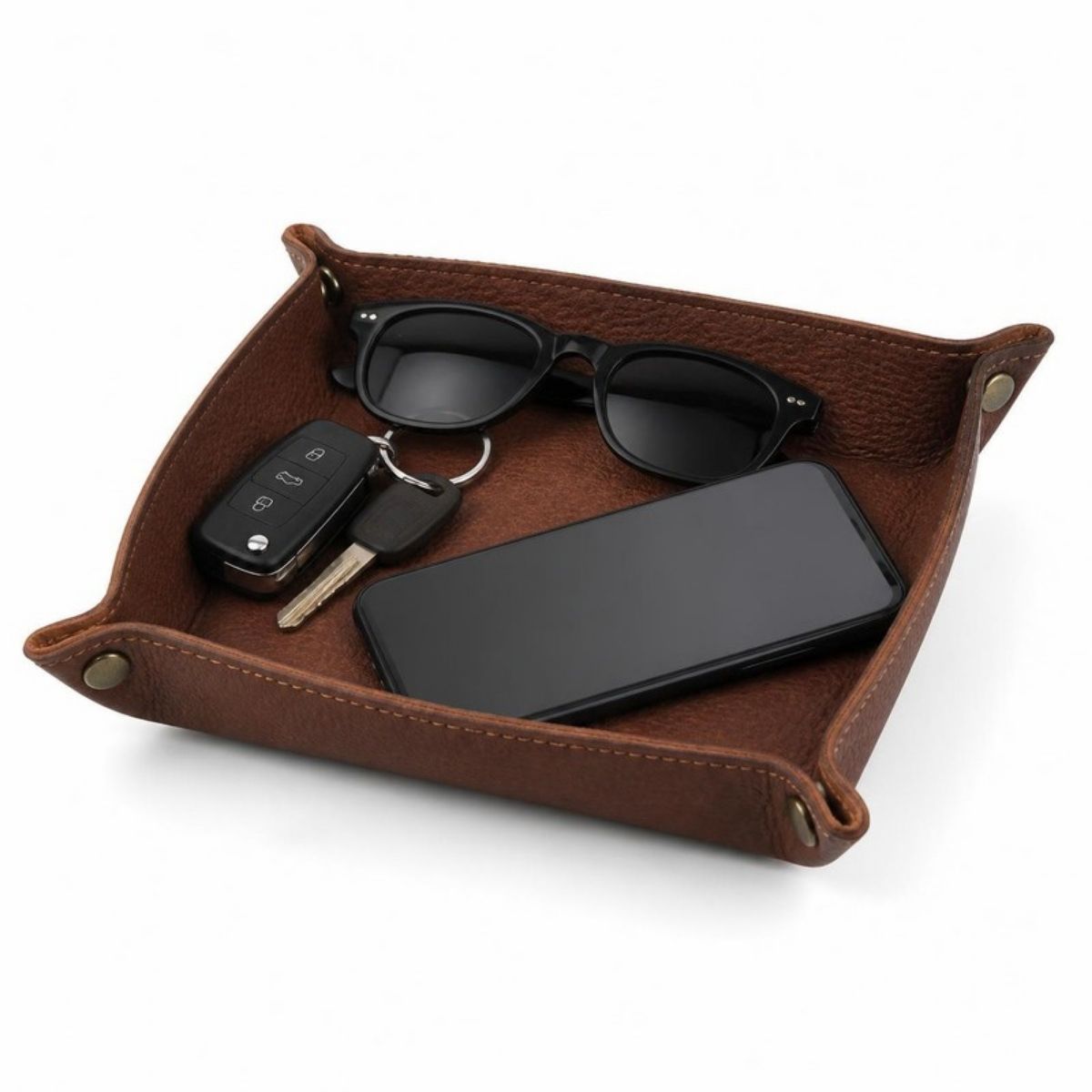 Brown leather valet tray holding keys, sunglasses and a phone