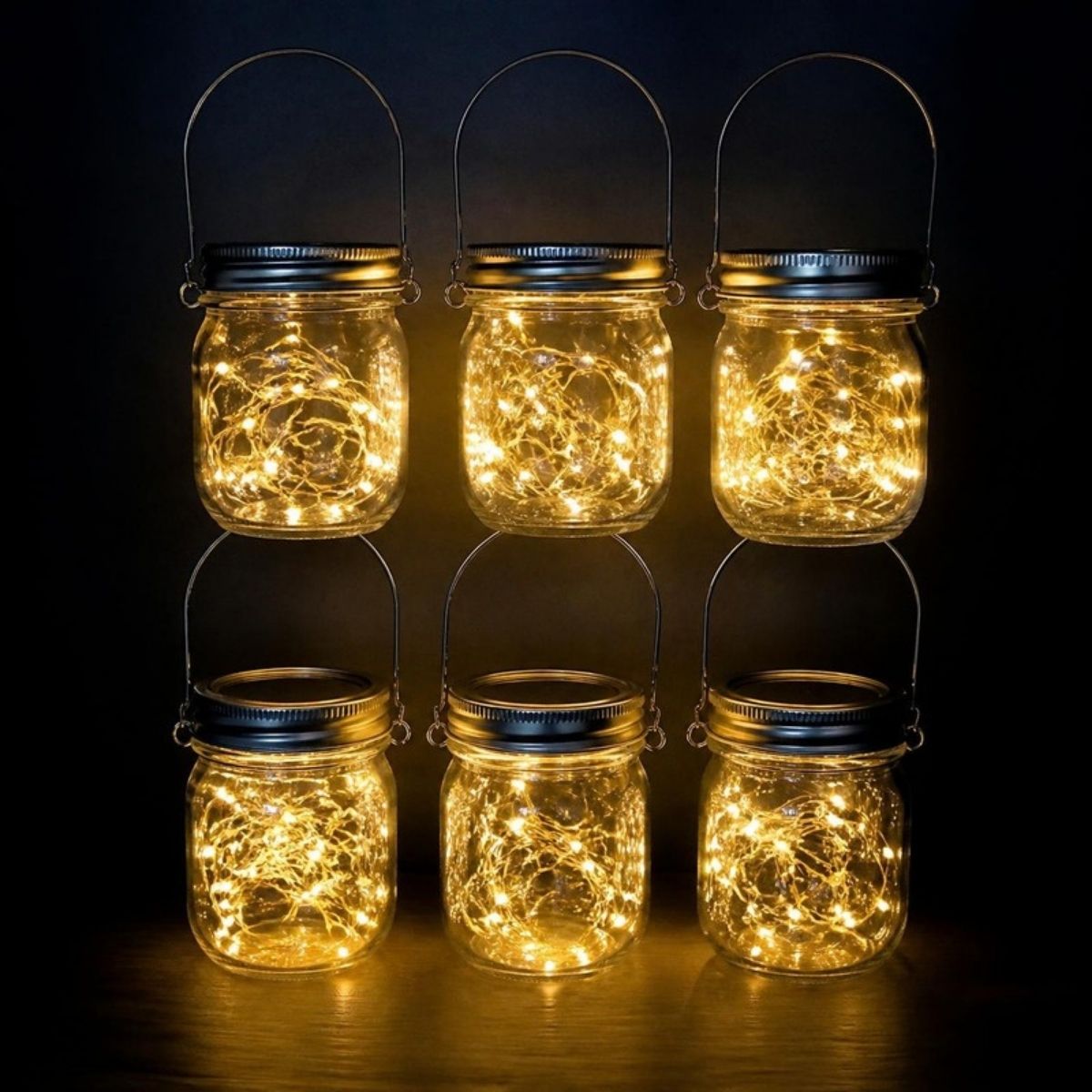 Six mason jars with handles glowing with warm fairy lights