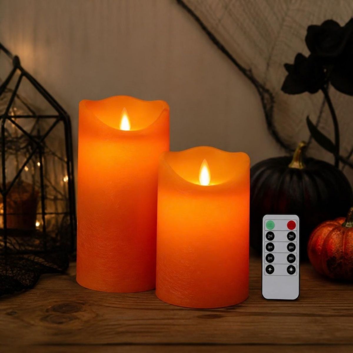 Two orange flameless pillar candles with a remote