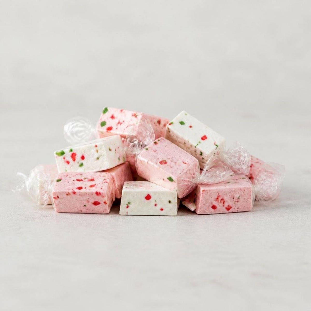 Pile of wrapped pink and white nougat candies with red and green bits