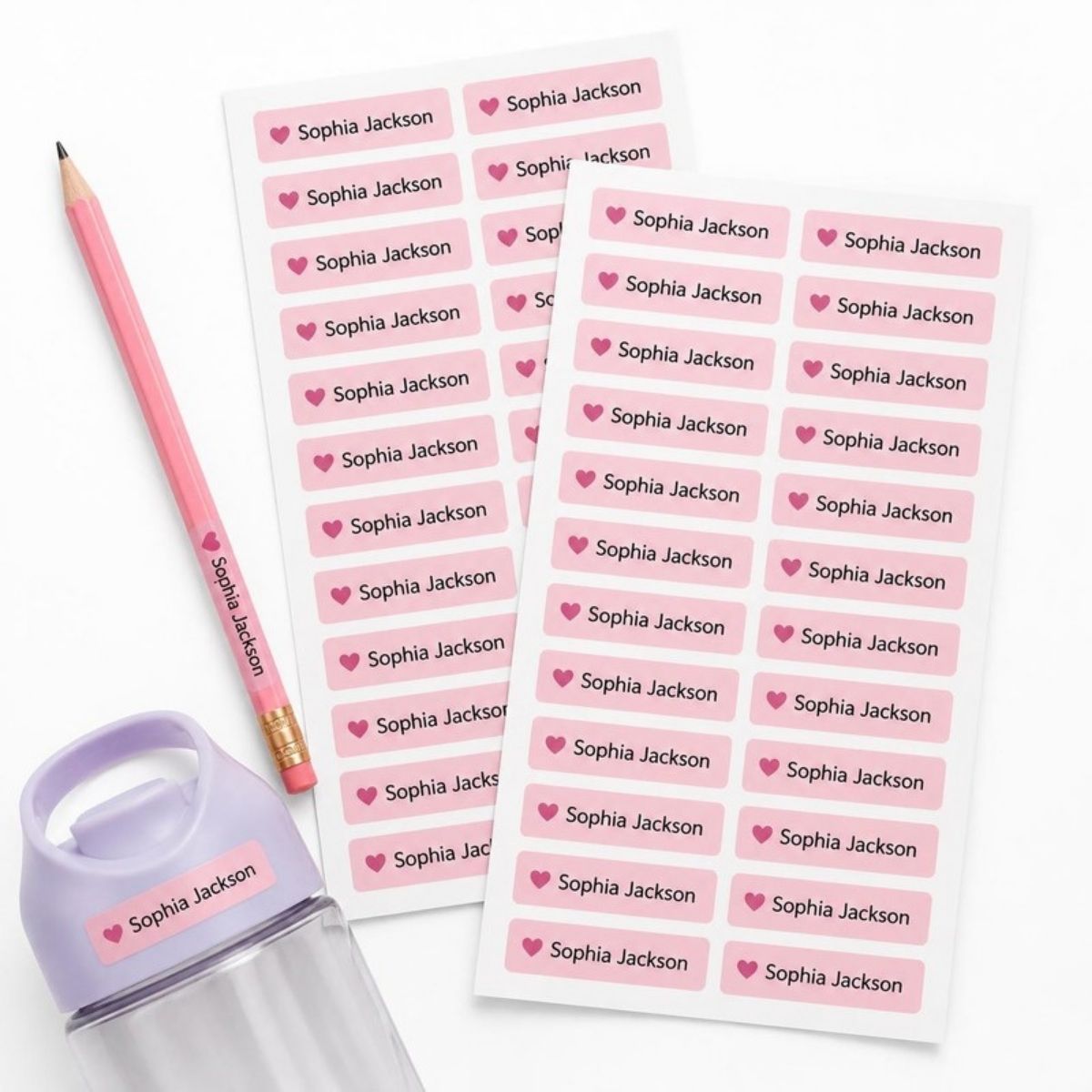 Sheets of pink name labels with a heart, on a pencil and water bottle