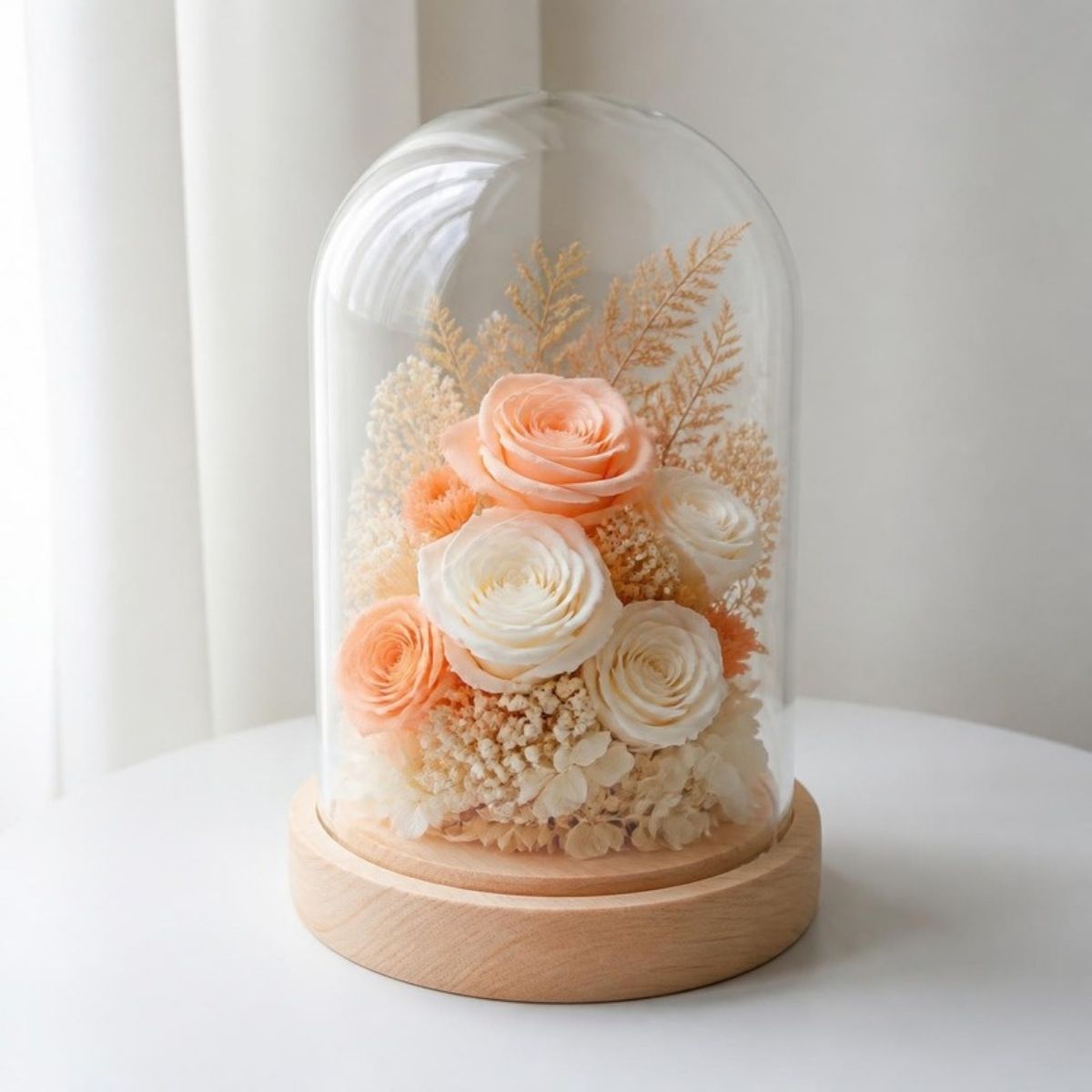 Peach and white preserved flowers under a glass dome