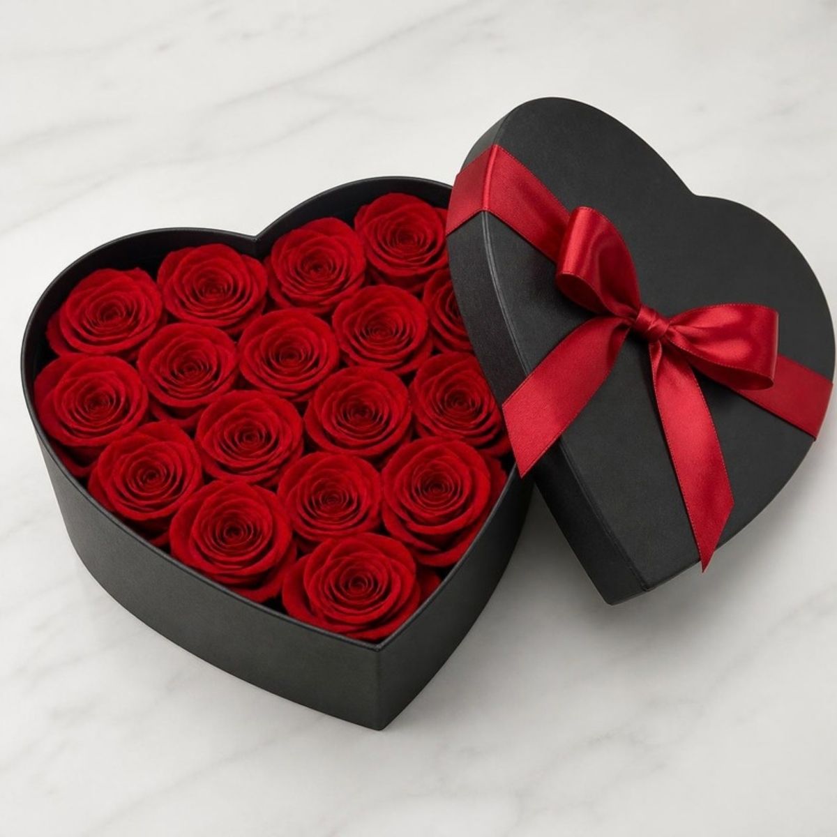 Black heart shaped box filled with red roses and a red bow
