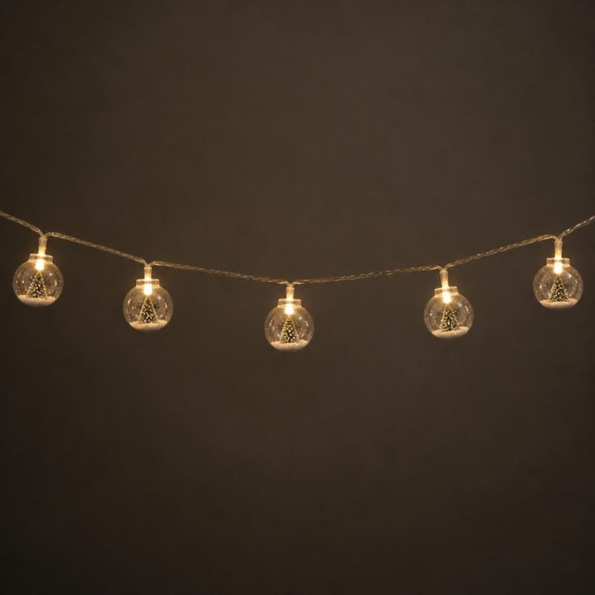 String of glowing snow globe bulbs, each with a tiny Christmas tree inside