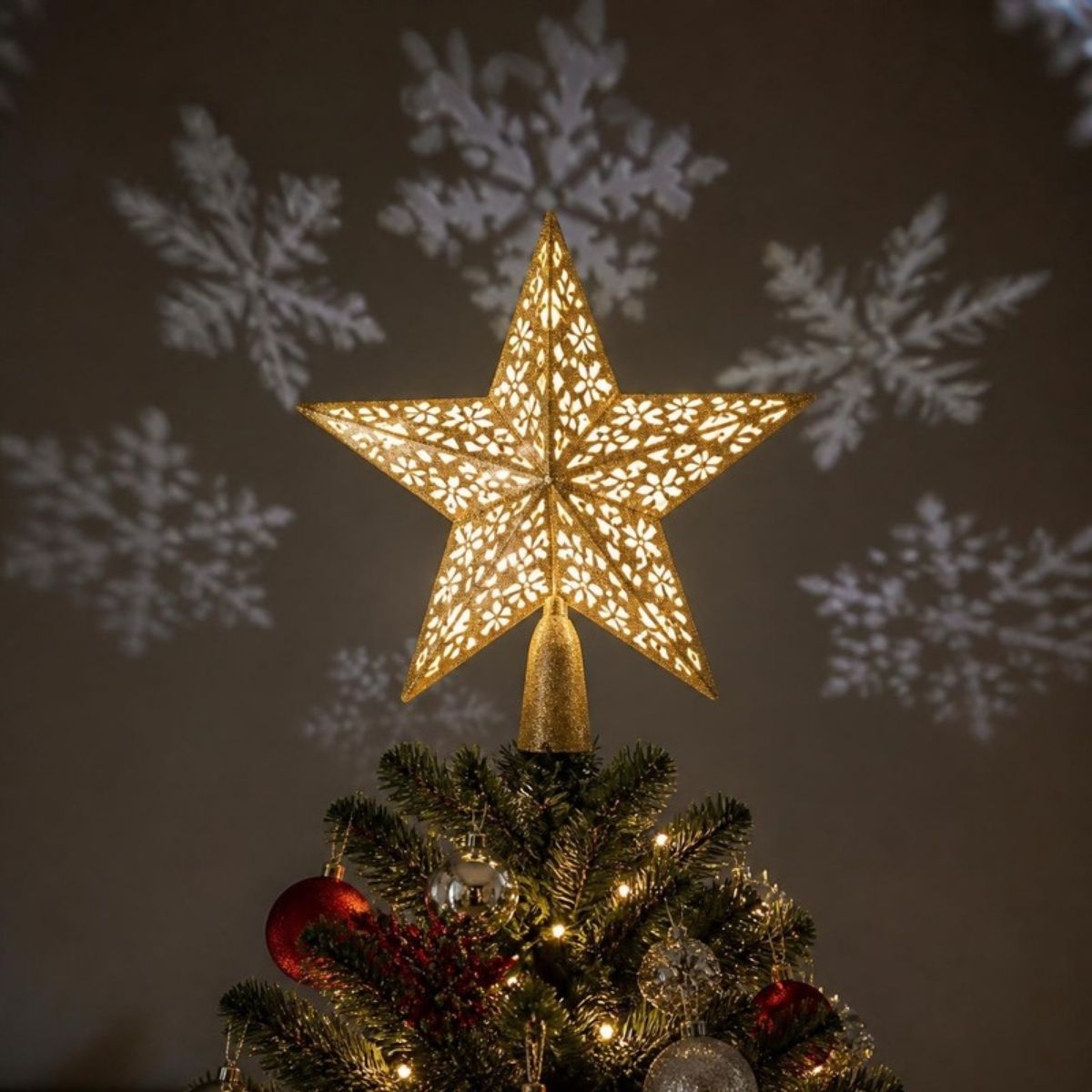 Glowing gold star tree topper projecting white snowflakes onto the wall