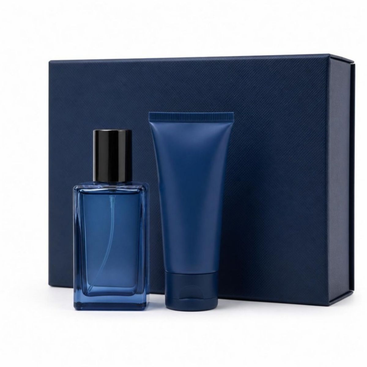 Small blue cologne bottle and shower gel tube in front of a navy gift box