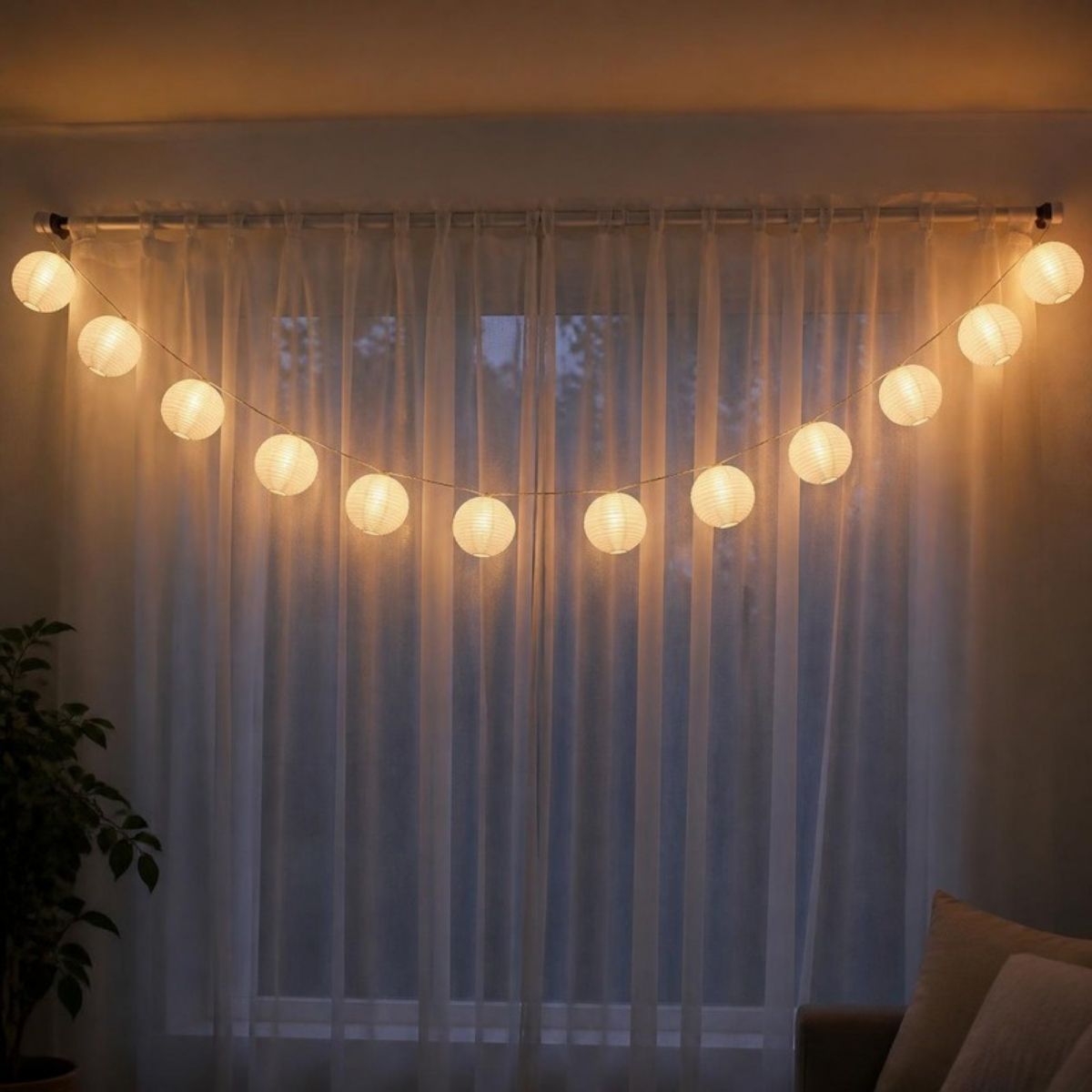 String of round white paper lantern lights glowing in a window